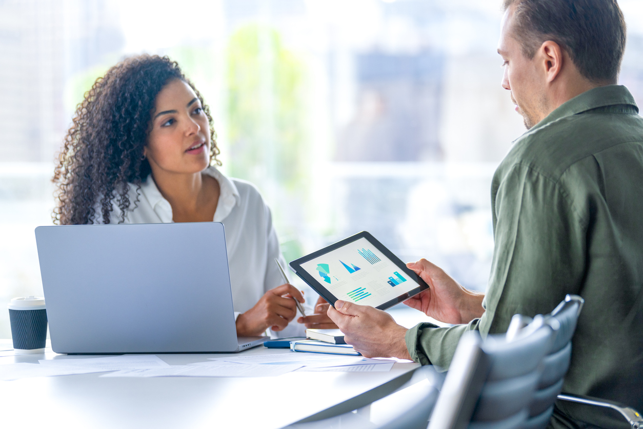A Health Policy Analyst Meets With a Colleague Holding a Tablet
