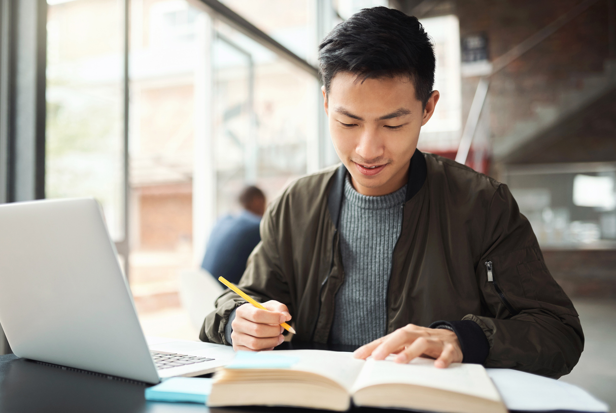 A Student Reading a Textbook and Taking Notes