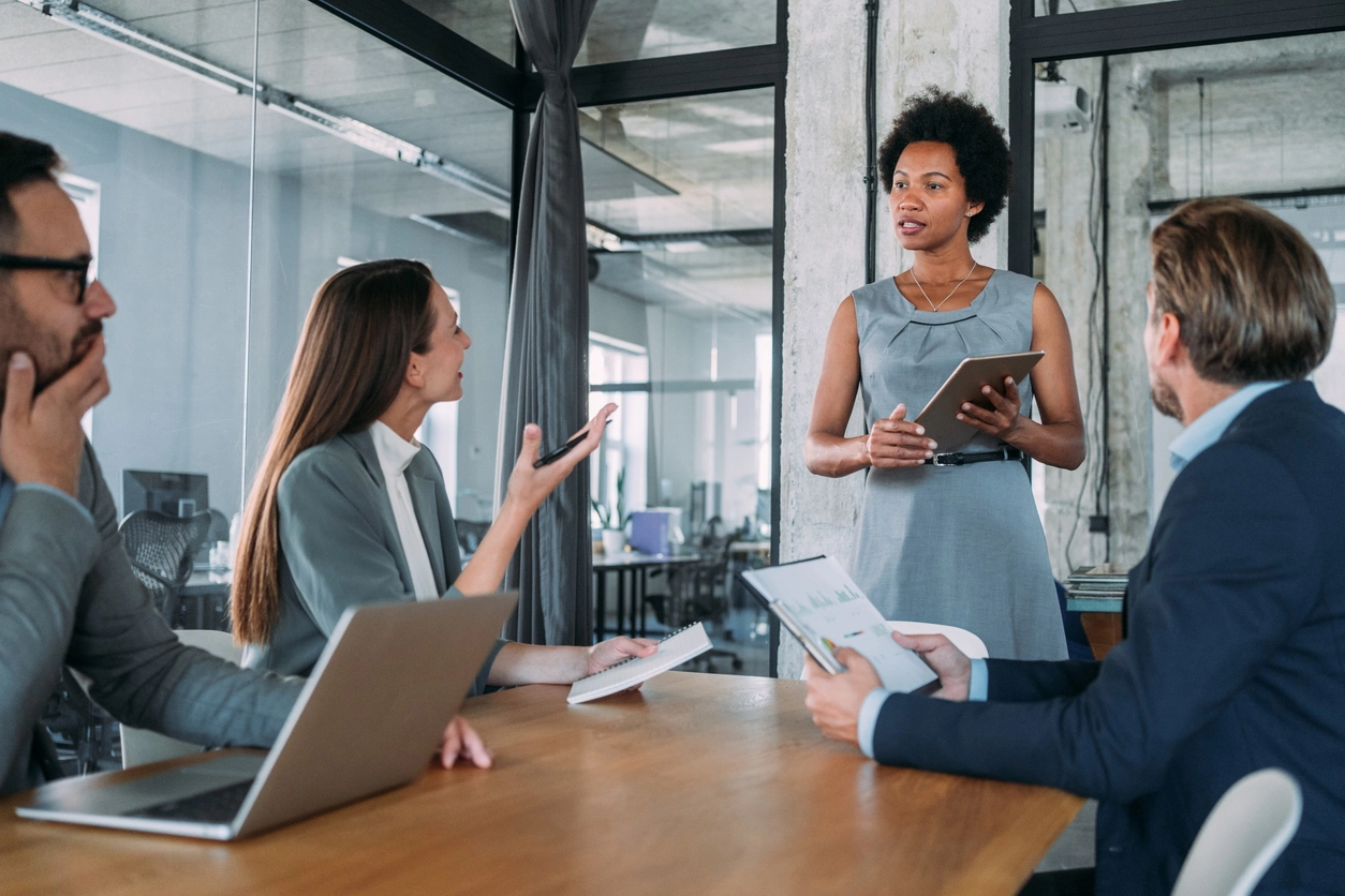 A manager leads a team meeting around a conference table.