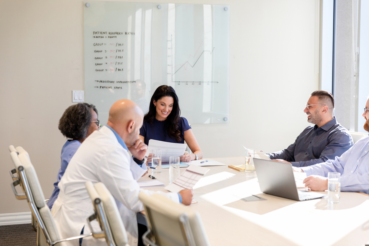 A health administrator and other health team members discuss patient recovery trends