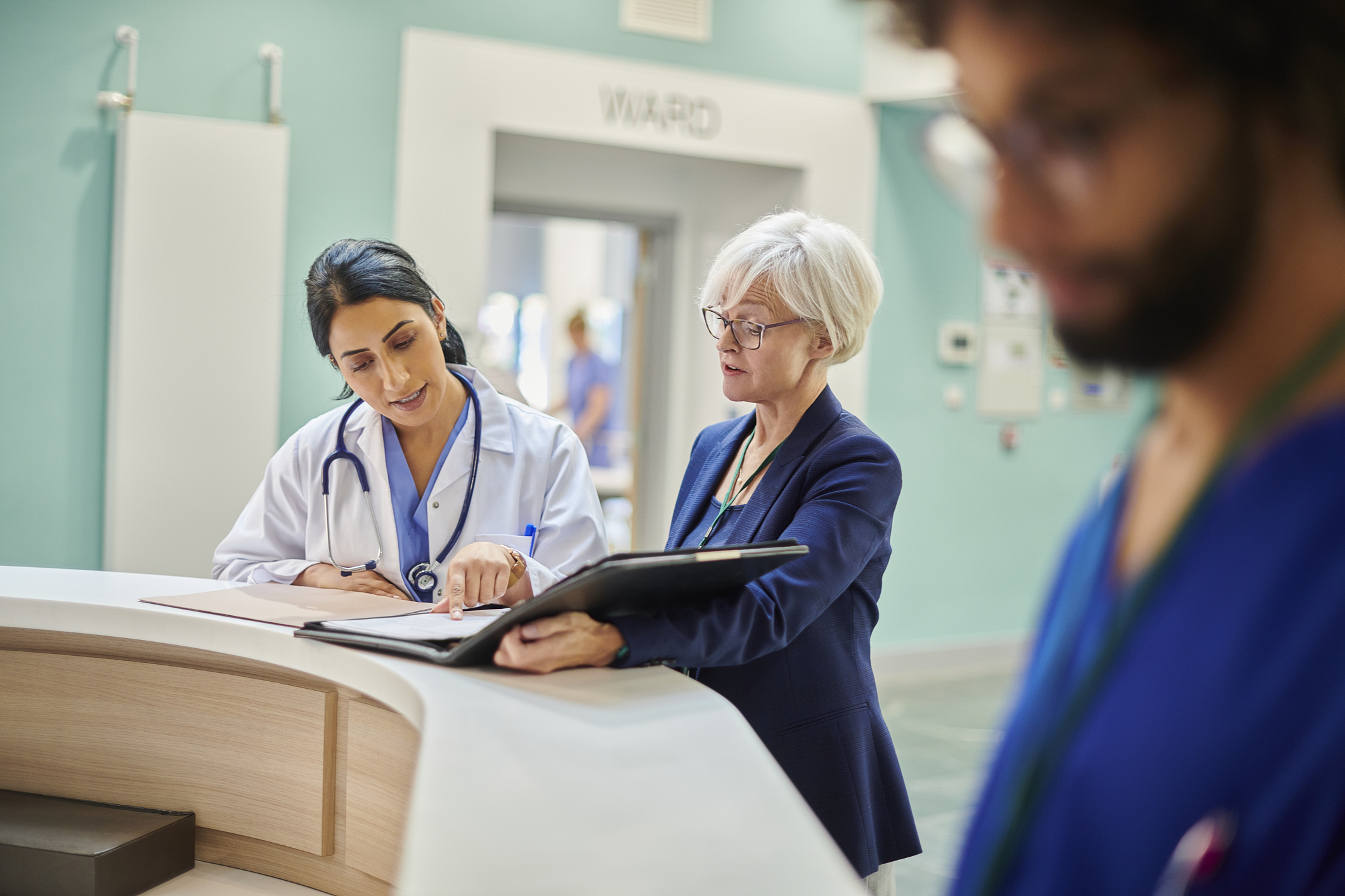A health administrator and a physician review a document in a hospital waiting room.