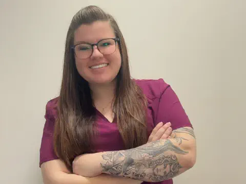 Ashley Adkins smiling and standing wearing scrubs.